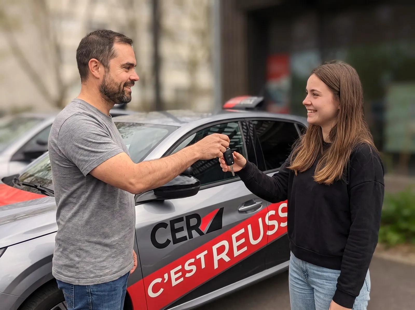 Aymeric, enseignant, remet les clés de la voiture-école à une élève